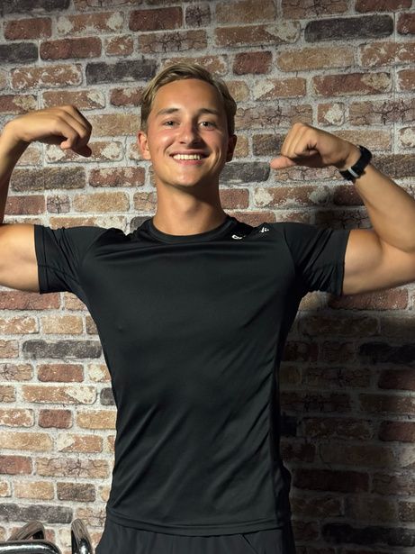 Stanislav lachend voor een bakstenen muur